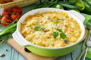 Casserole crumble with red fish, white bread and cheese on the kitchen wooden table.