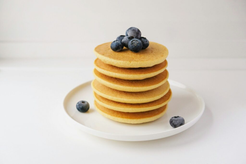 Homemade gluten-free pancakes stacked on white plate.