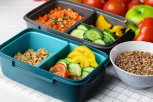 Lunch box with cooked buckwheat and fresh vegetable salad