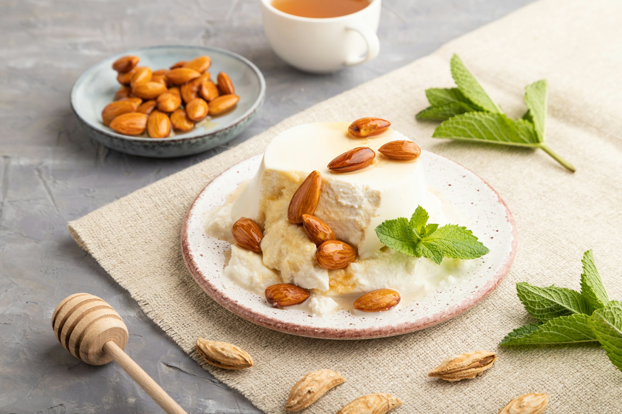 Ricotta cheese with honey and almonds on gray concrete. side view, close up.