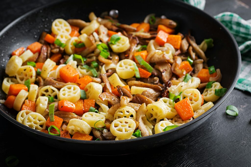 Rotelle pasta gluten free with mushrooms and pumpkin on a dark background.